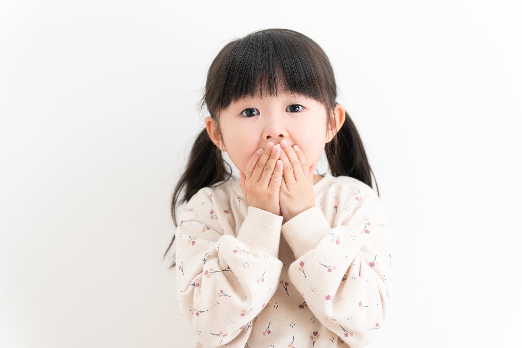 出っ歯を気にして口を押える子ども