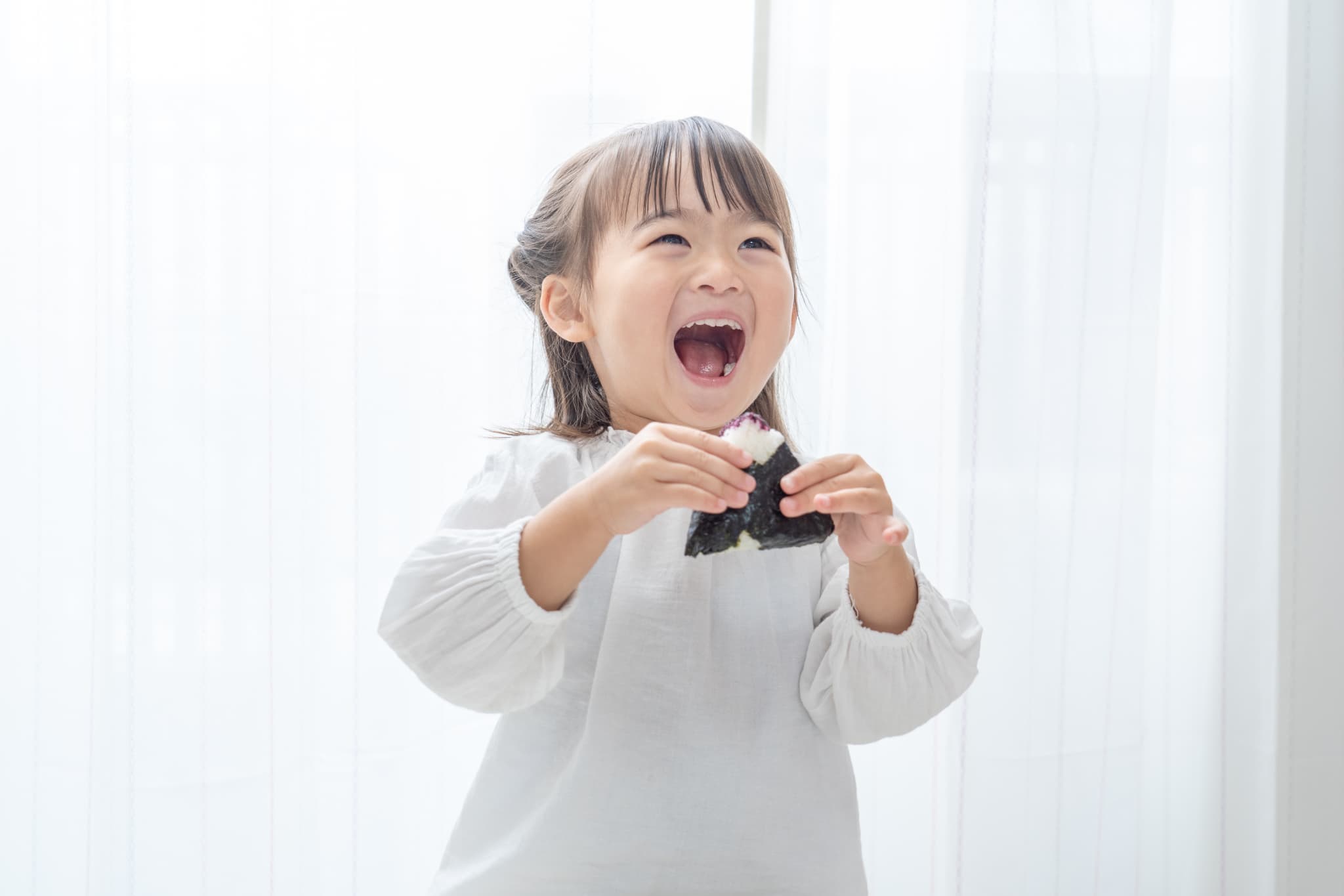 しっかり噛んでおにぎりを食べる子ども