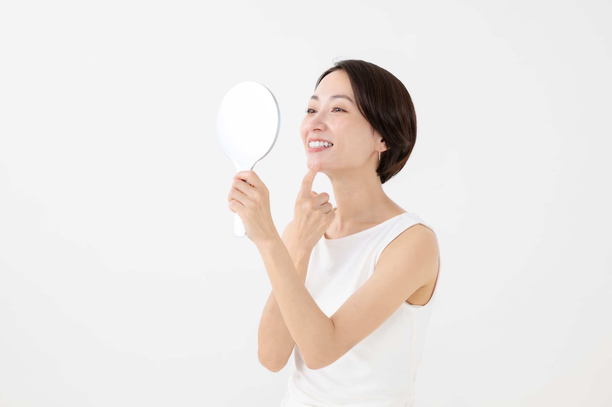 セラミックの歯が気になって鏡で見ている女性