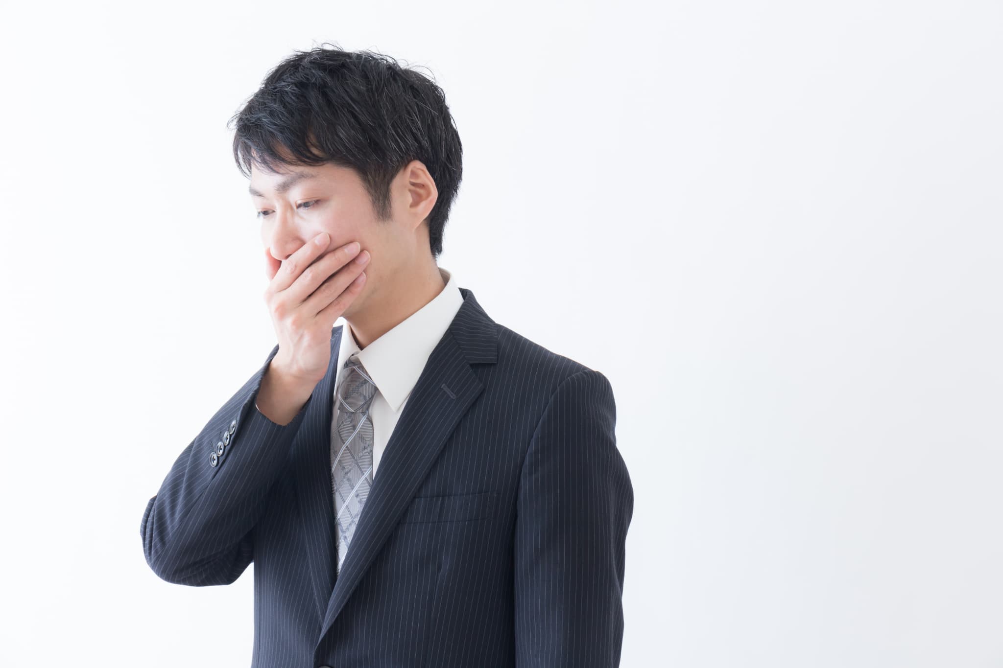 口臭を気にして口を押える男性