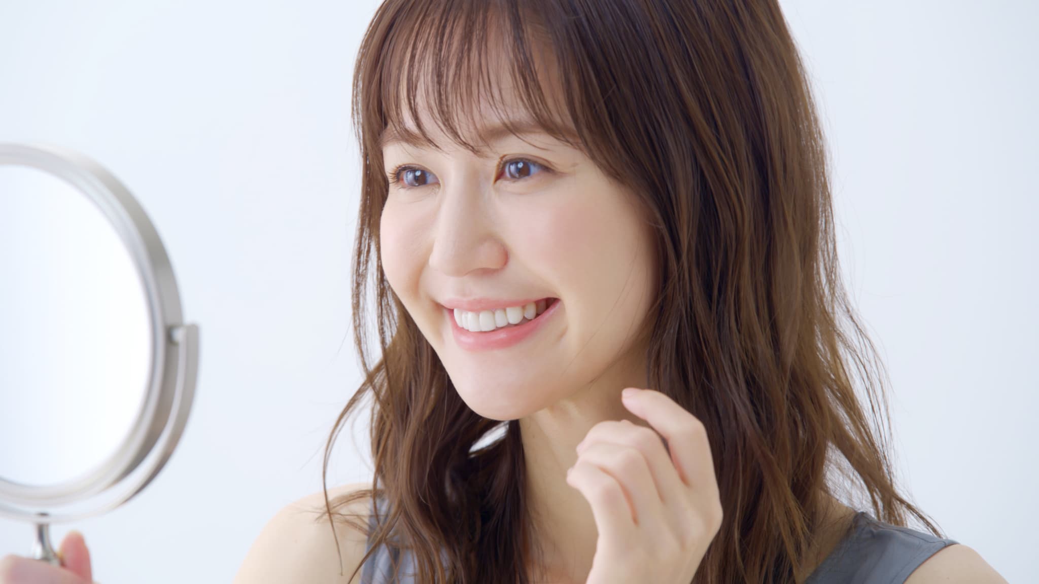 矯正をして整った歯を鏡で確認する笑顔の女性