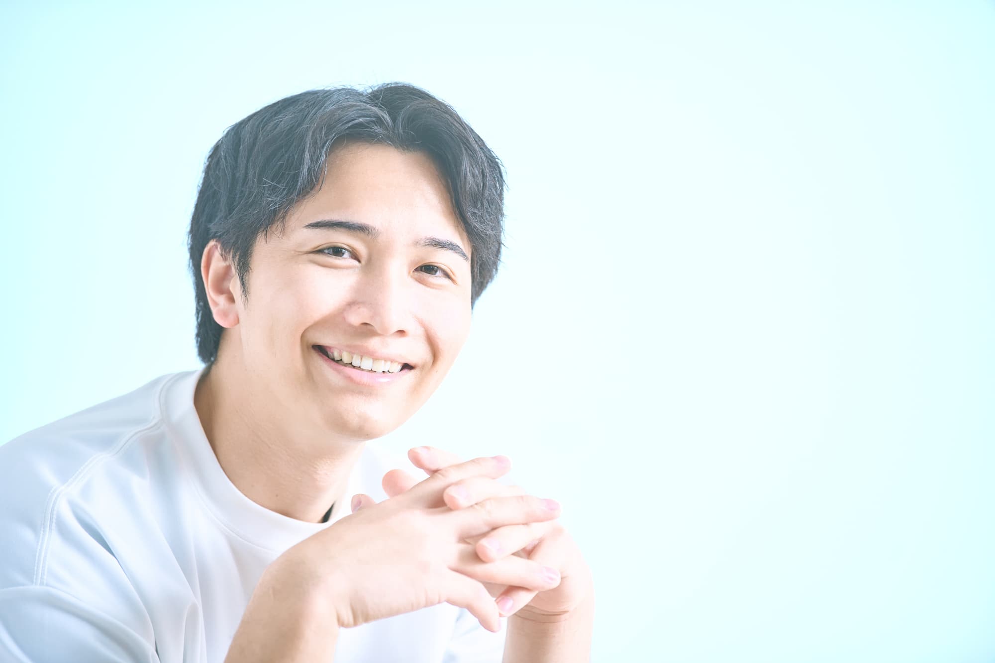 手を組み笑顔の男性