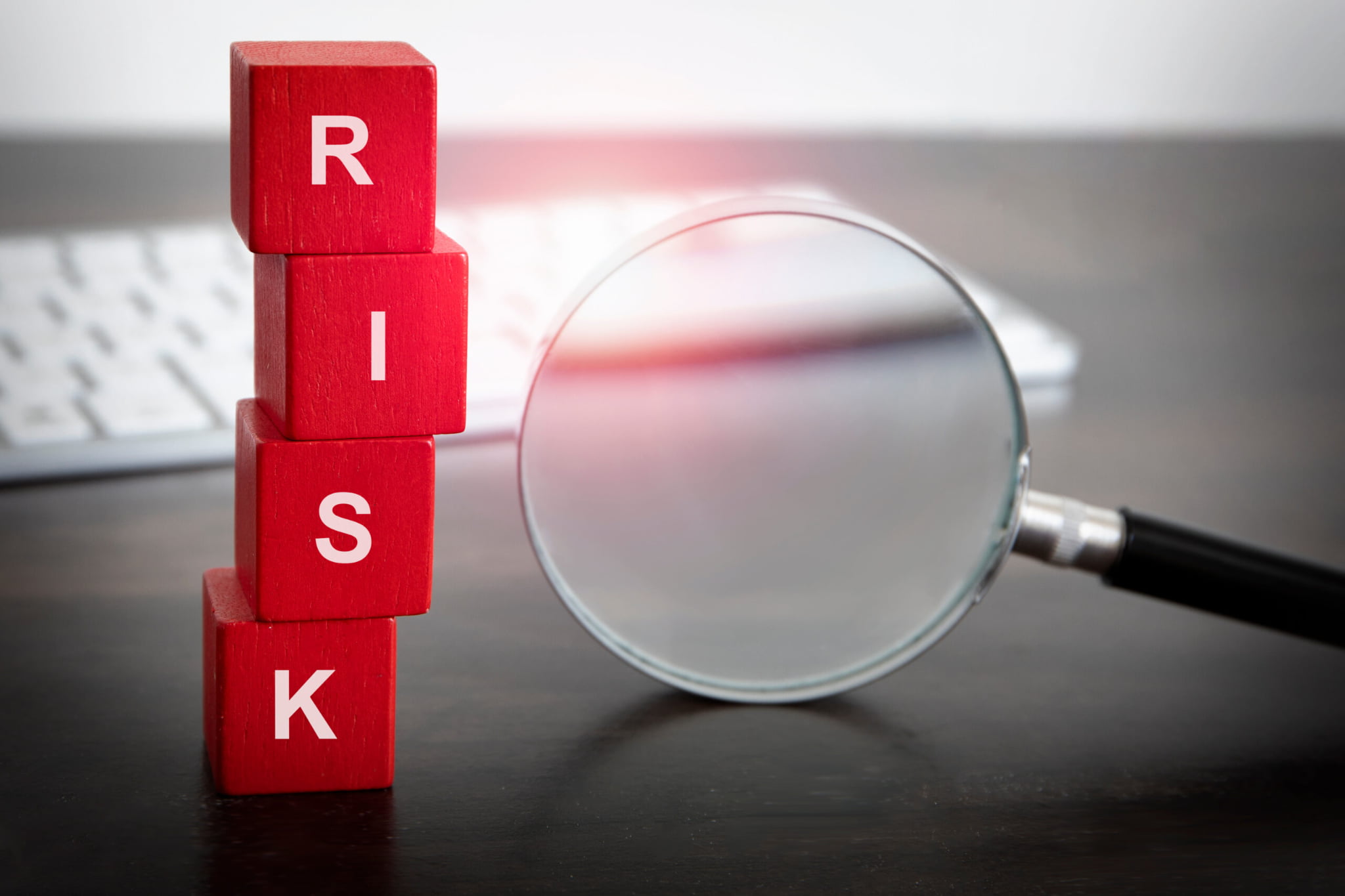 リスクと書かれた赤い積み木と虫眼鏡